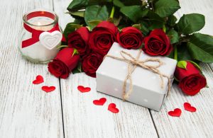 a candle, gift box, and red roses