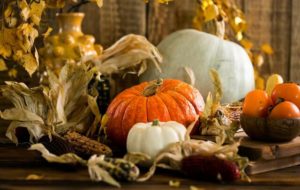 a decorative autumn display with pumpkins, gourds, and corn