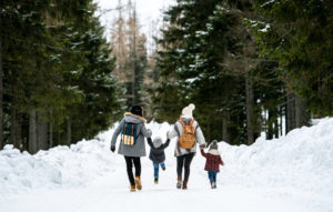 family dressed in outerwear enjoying a snowy path