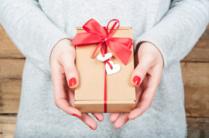 Hands holding gift in kraft box on a wooden background